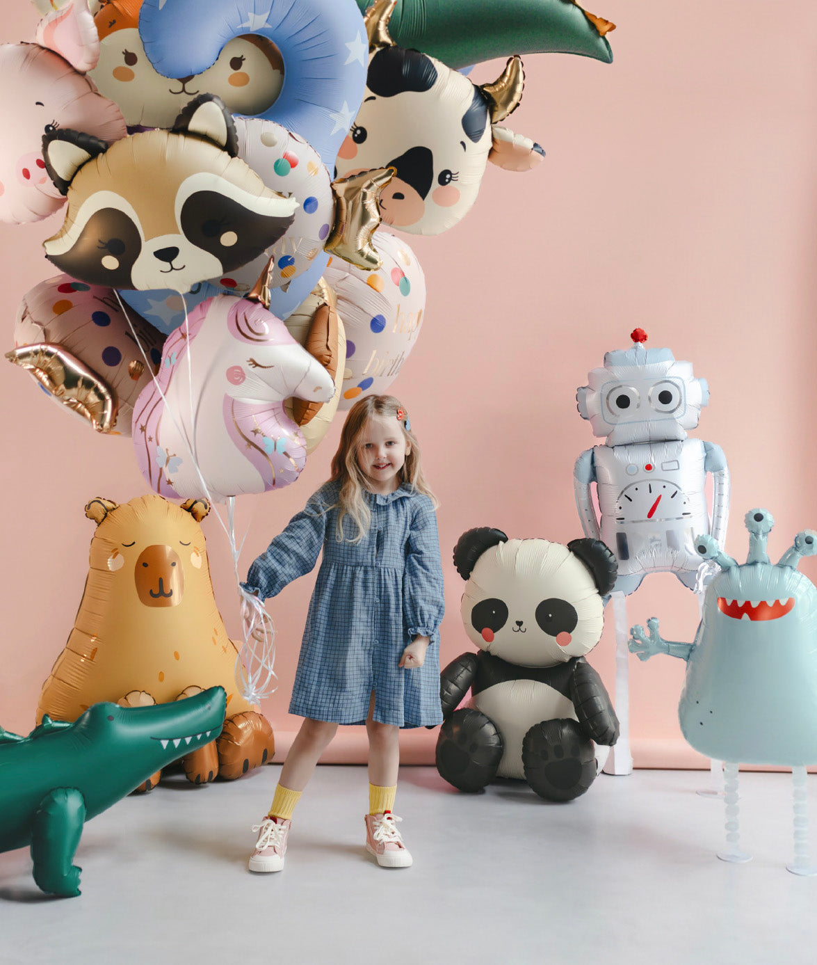 "Girl holding unicorn foil balloon with colorful animal balloons backdrop"